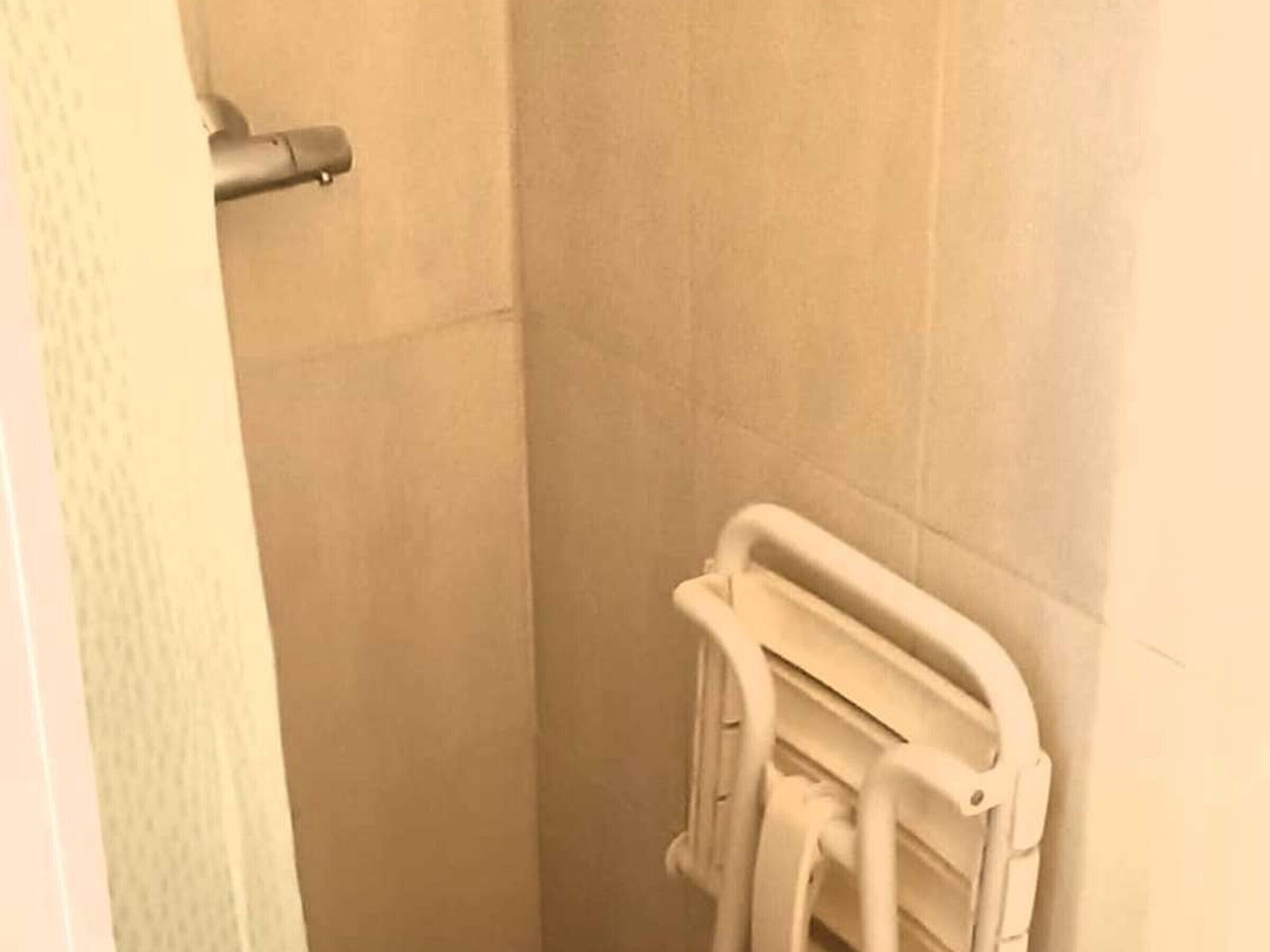 Un baño con cabina de ducha blanca, toallero blanco y una toalla blanca.