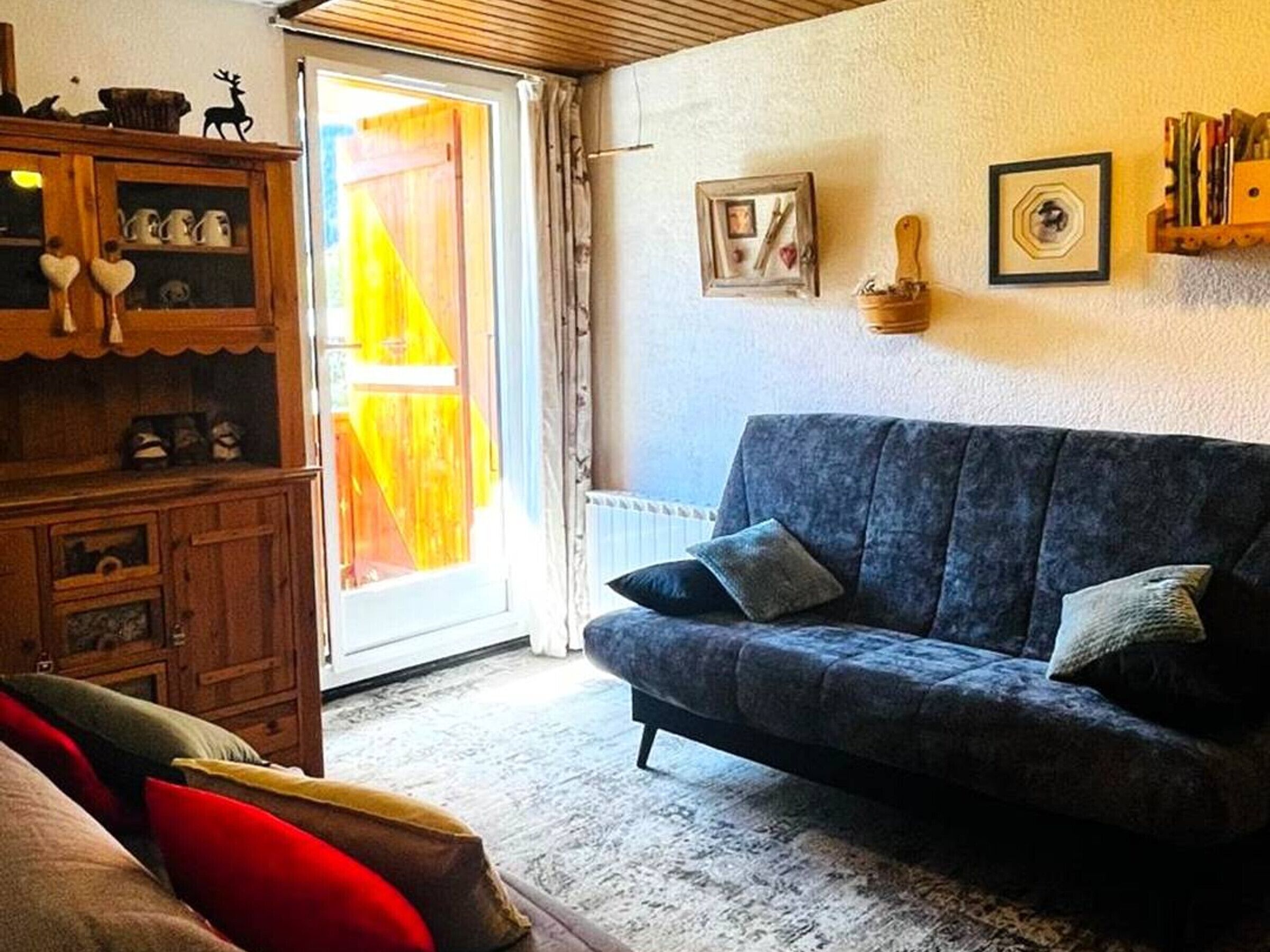 Ett vardagsrum med en soffa, ett träskåp och en dörr som leder ut till ett utomhusområde.