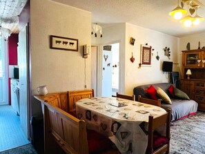 A cozy living room with a dining table, a sofa, and a television. - Comfortable apartment, ski-in access - 4 guests (Les Gets)