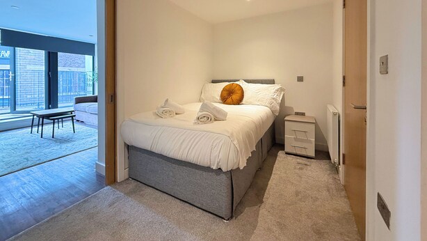 A modern bedroom with a bed, bedside tables, and a view of the outside. - Chic 1-Bed Flat in Sheffield City Centre (Sheffield)