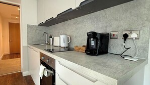 A modern kitchen with white cabinets, a built-in oven, a coffee maker, and a power outlet. - Chic 1-Bed Flat in Sheffield City Centre (Sheffield)