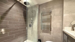 A modern bathroom with a glass-enclosed shower, a toilet, and a towel rack. - Chic 1-Bed Flat in Sheffield City Centre (Sheffield)