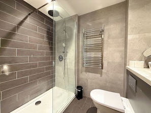 Ein modernes Badezimmer mit einer einteiligen Duschkabine, Toilette und Handtuchhalter.