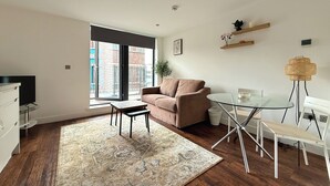 A modern living room with a sofa, a glass table, and a coffee table. - Chic 1-Bed Flat in Sheffield City Centre (Sheffield)