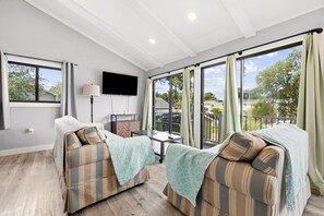 A modern room with two sofas, a flat-screen TV, and large windows. - Walk to the Beach, North Myrtle Beach Getaway (North Myrtle Beach)