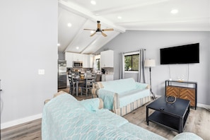 A modern living room with a sofa, a coffee table, and a television mounted on the wall. - Walk to the Beach, North Myrtle Beach Getaway (North Myrtle Beach)