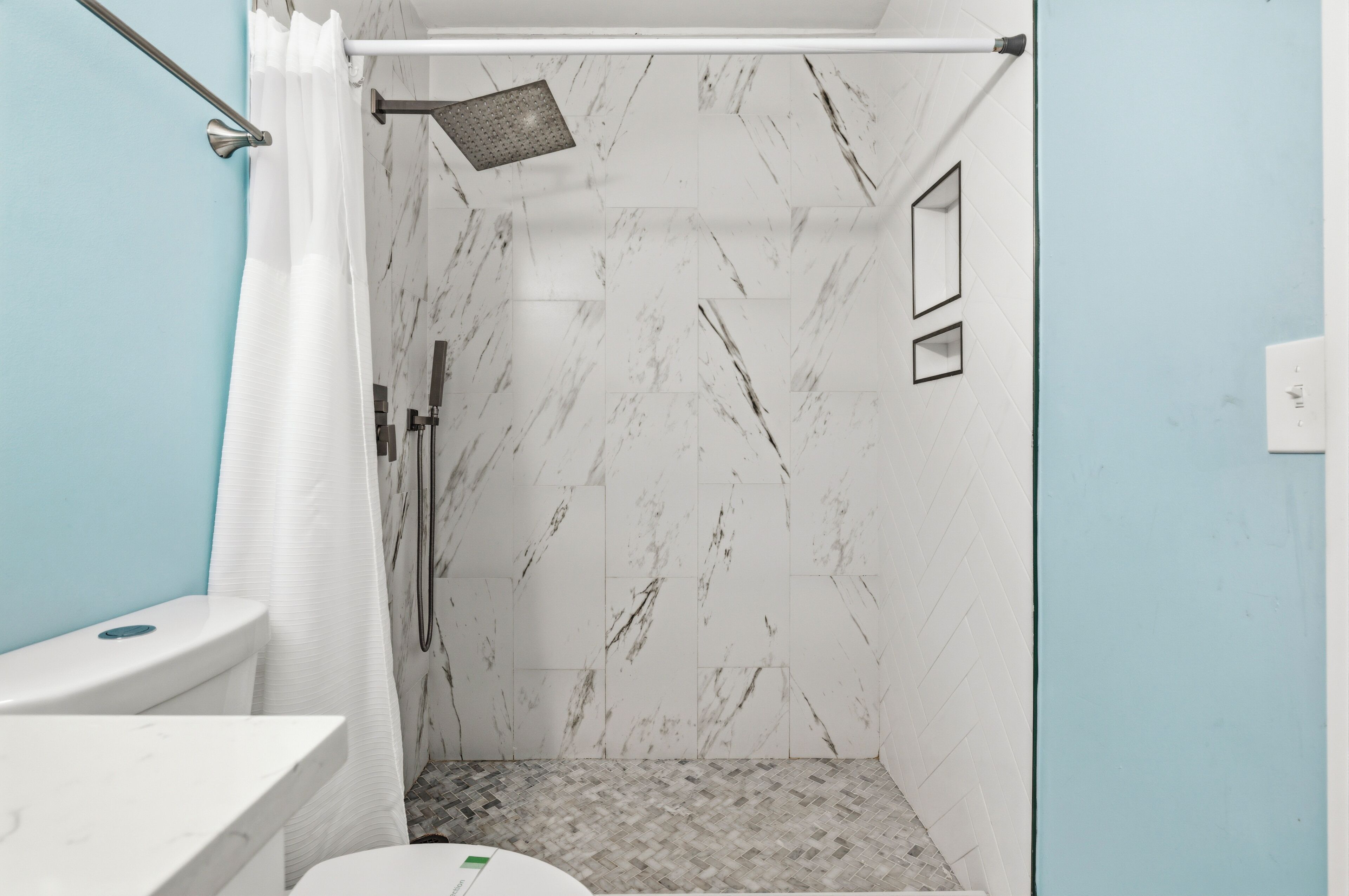 Une salle de bain avec douche, toilettes et murs en marbre.