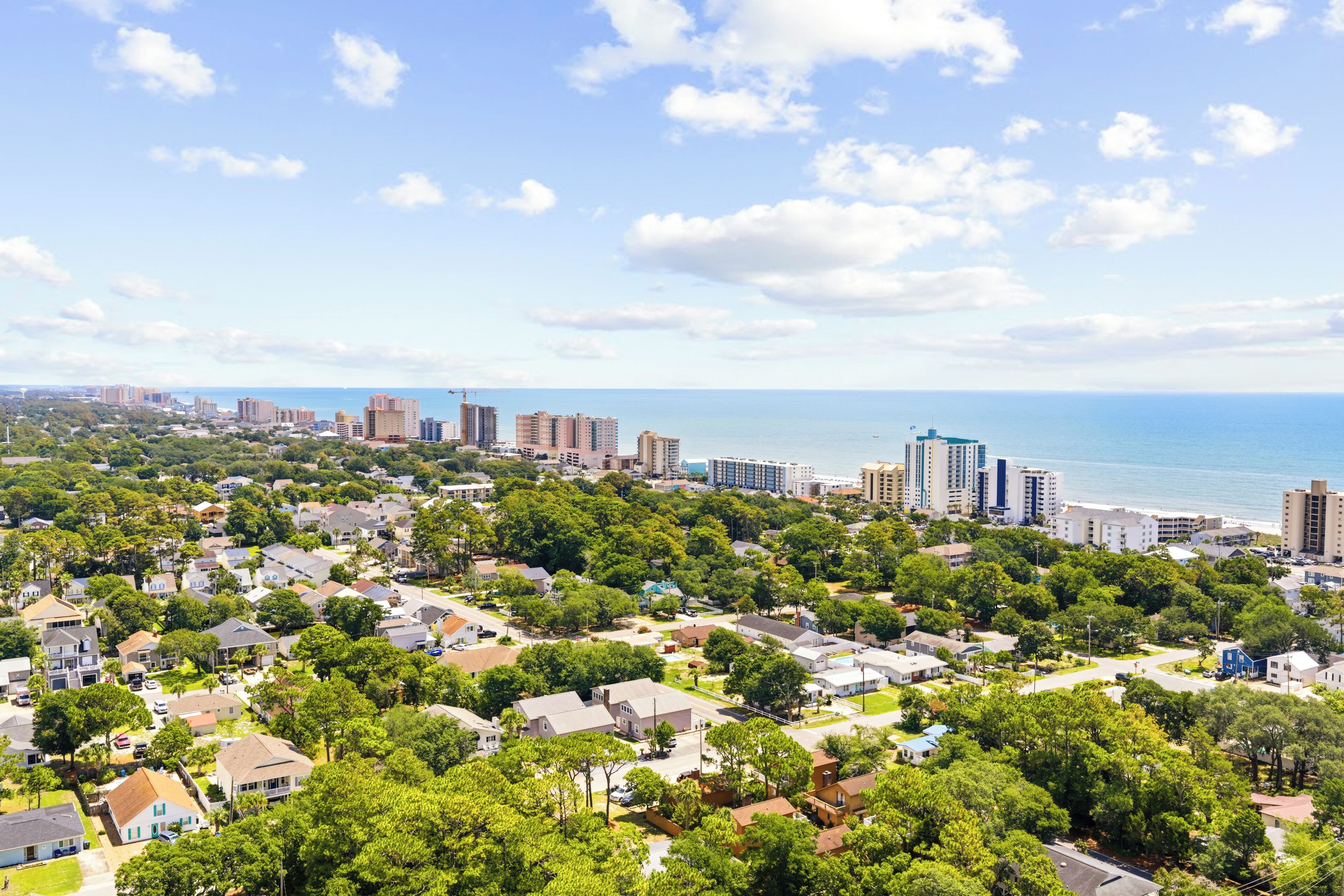 A residential area with houses, trees, and a view of the ocean.