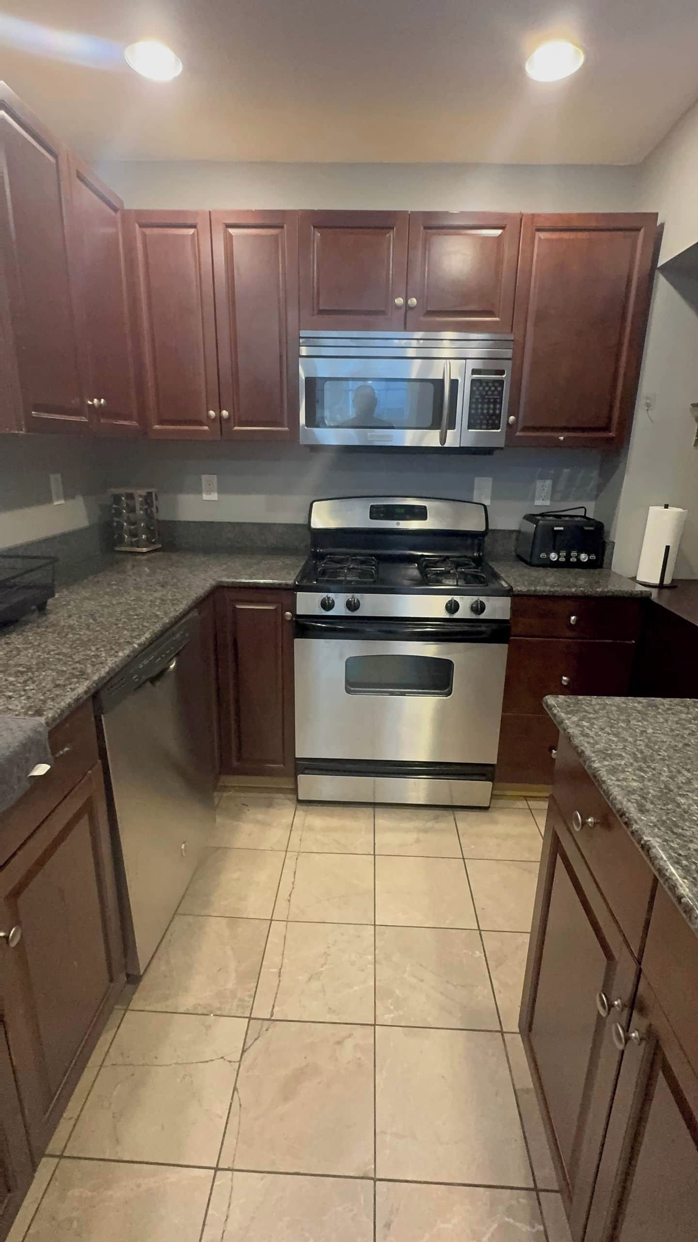 A kitchen with wooden cabinets, a stainless steel stove, and a microwave.