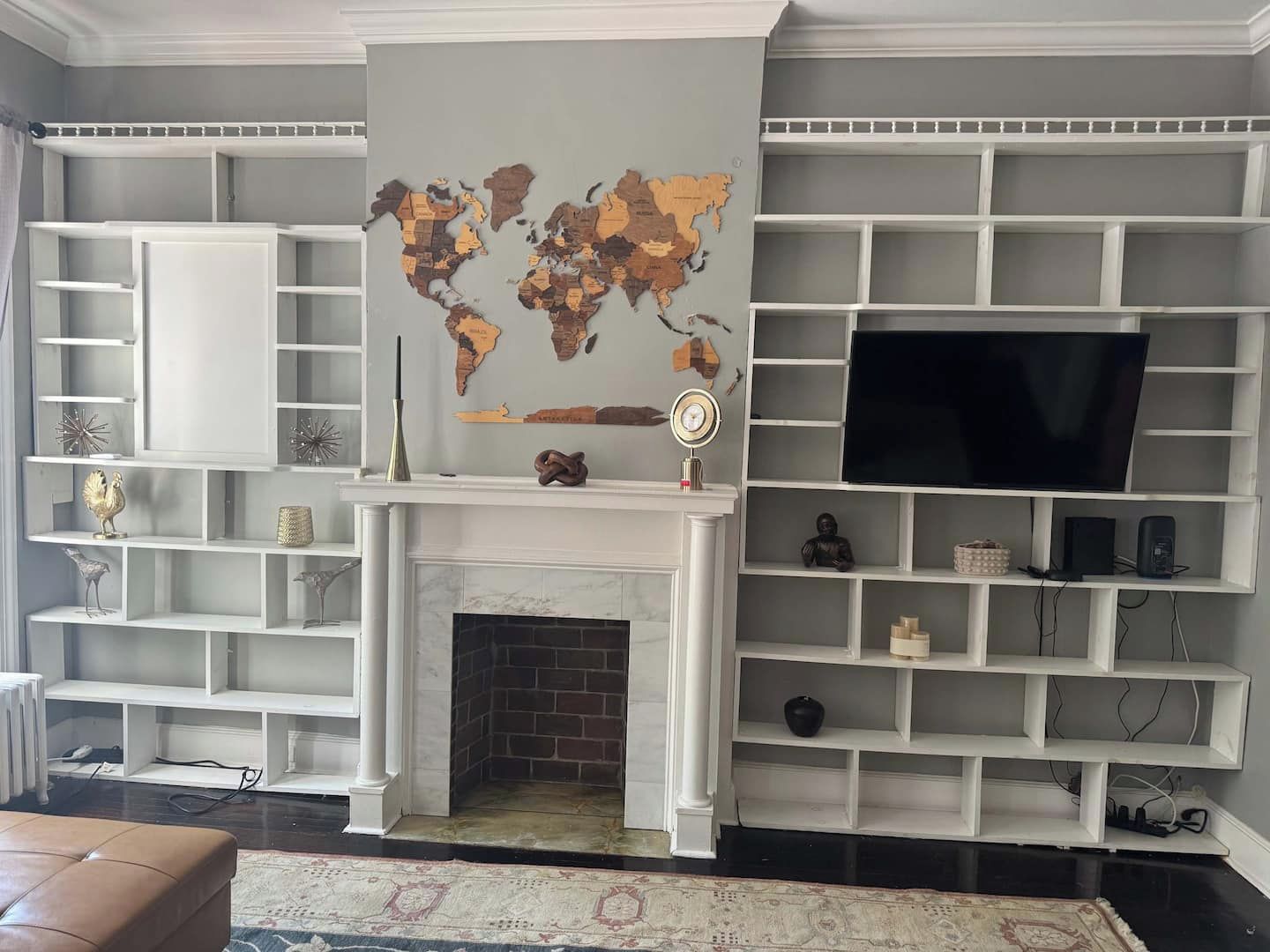 A living room with a fireplace, a world map, and a television on a white wall.