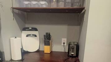 Et kompakt køkken med bordplade, kaffemaskine, brødrister og knivblok.