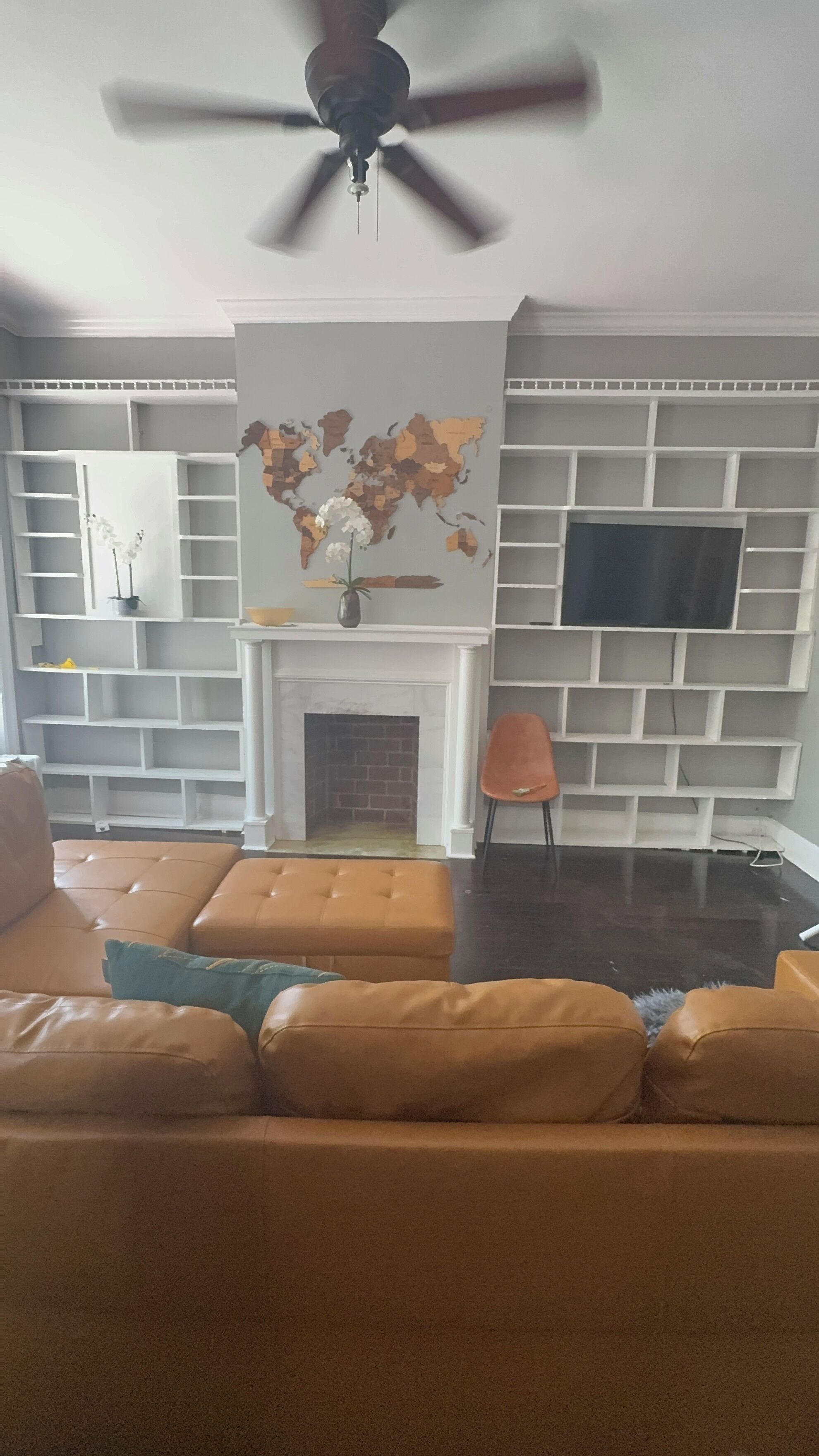 A living room with a sofa, a television, a fireplace, and a world map on the wall.
