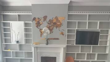 A living room with a sofa, a television, a fireplace, and a world map on the wall.
