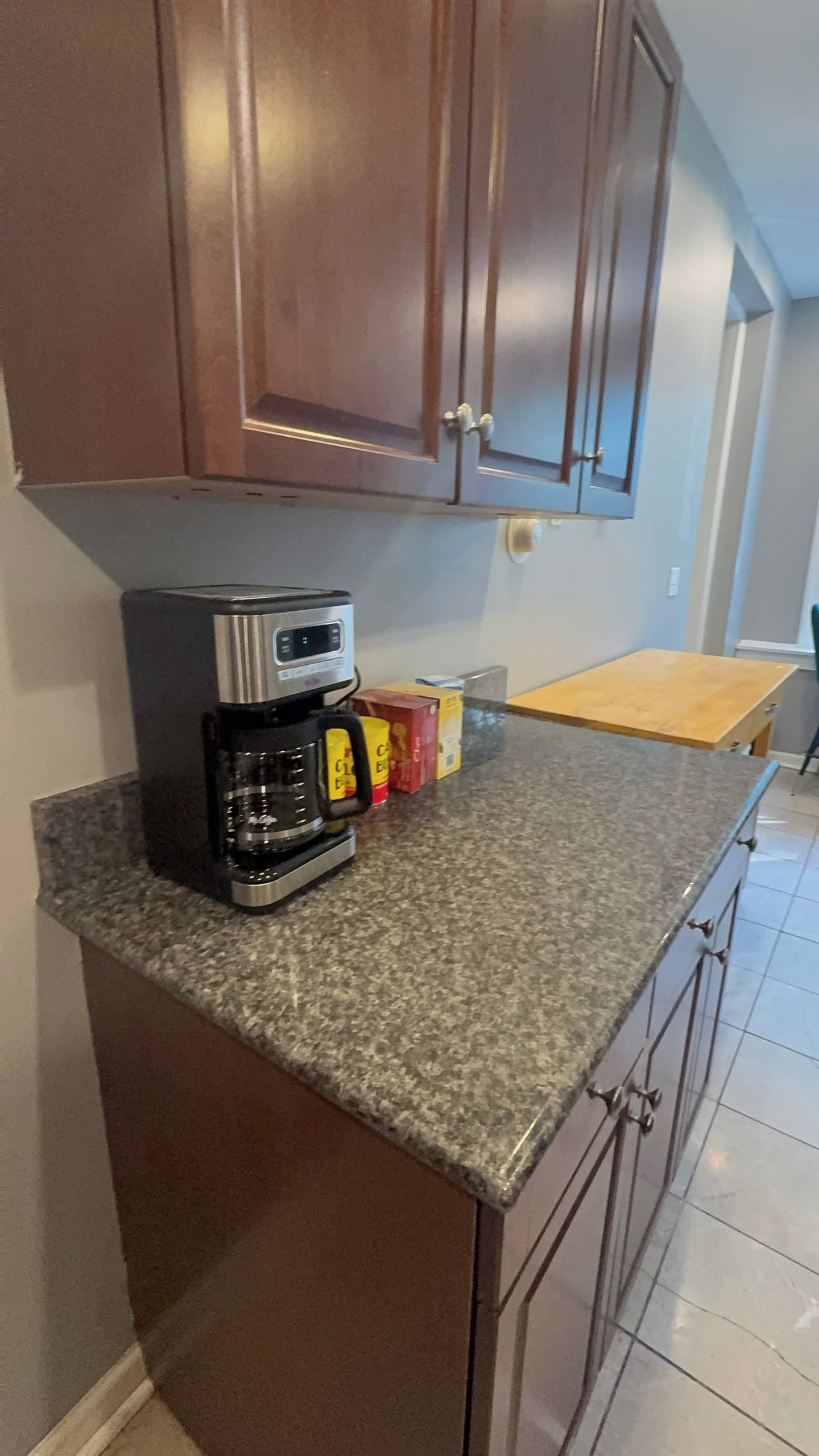 A kitchen with dark wooden cabinets, a granite countertop, a coffee maker, and a toaster.