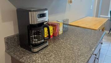 A kitchen with dark wooden cabinets, a granite countertop, a coffee maker, and a toaster.