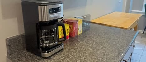 A kitchen with dark wooden cabinets, a granite countertop, a coffee maker, and a toaster.