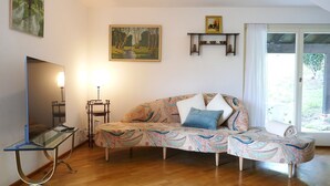 Uma sala de estar aconchegante com um sofá, uma TV de tela plana, um abajur e um quadro na parede.