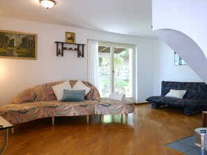 A living room with two sofas, a painting, and a window with a view of greenery. - Casa Alenzino by Interhome (Corzoneso)