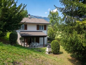 Ein zweistöckiges Haus mit einer Terrasse und einem Grill im Vorgarten.
