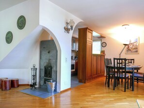 Ein geräumiger Wohnbereich mit Kamin, einem Holzesstzimmer und einer durch einen Bogen sichtbaren Küche.