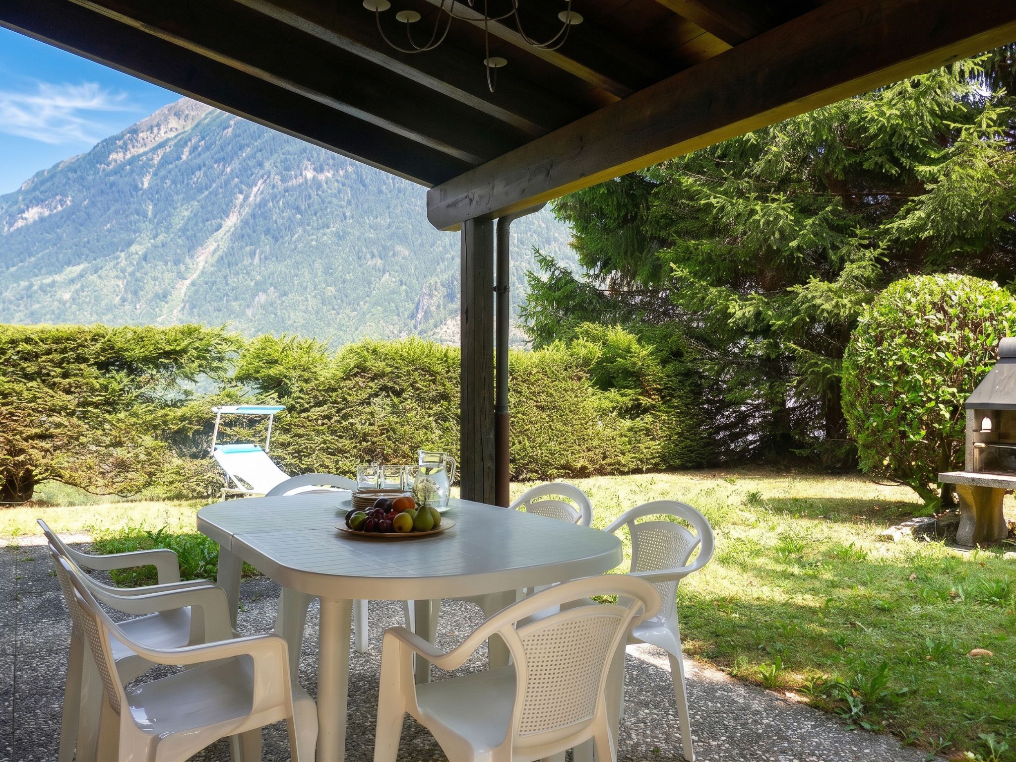 Ein Essbereich im Freien mit einem Tisch für zwei Personen, umgeben von Stühlen, mit Blick auf eine Berglandschaft.