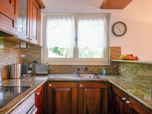 Eine Küche mit Holzausstattung, einem Edelstahl-Spülbecken, einem Toaster und einer Uhr an der Wand.
