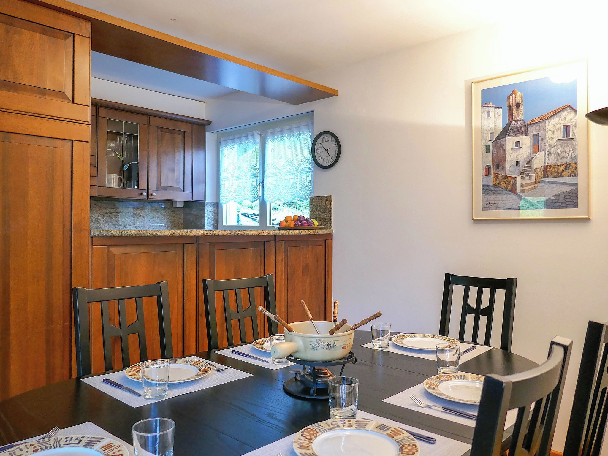 Comedor con armarios de madera, un reloj y un cuadro enmarcado.