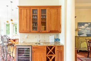 Cozinha com armários de madeira, bancada de mármore e vista para a sala de jantar.