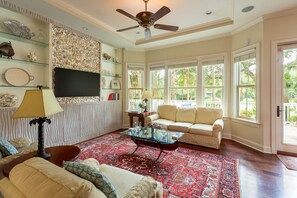 Una sala de estar con sofá, sillón, mesa de centro y objetos decorativos en estanterías.