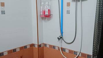 A shower with a blue pipe, a glass soap dispenser, and a control unit on the wall.
