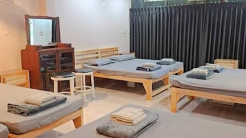 Habitación de hotel con dos camas, un espejo, un televisor y una ventana con cortinas.