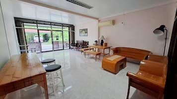 A spacious room with a large window, a wooden table, a sofa, and a lamp.