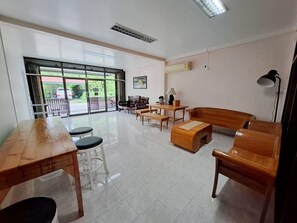 Una habitación amplia con un ventanal grande, una mesa de madera, un sofá y una lámpara.