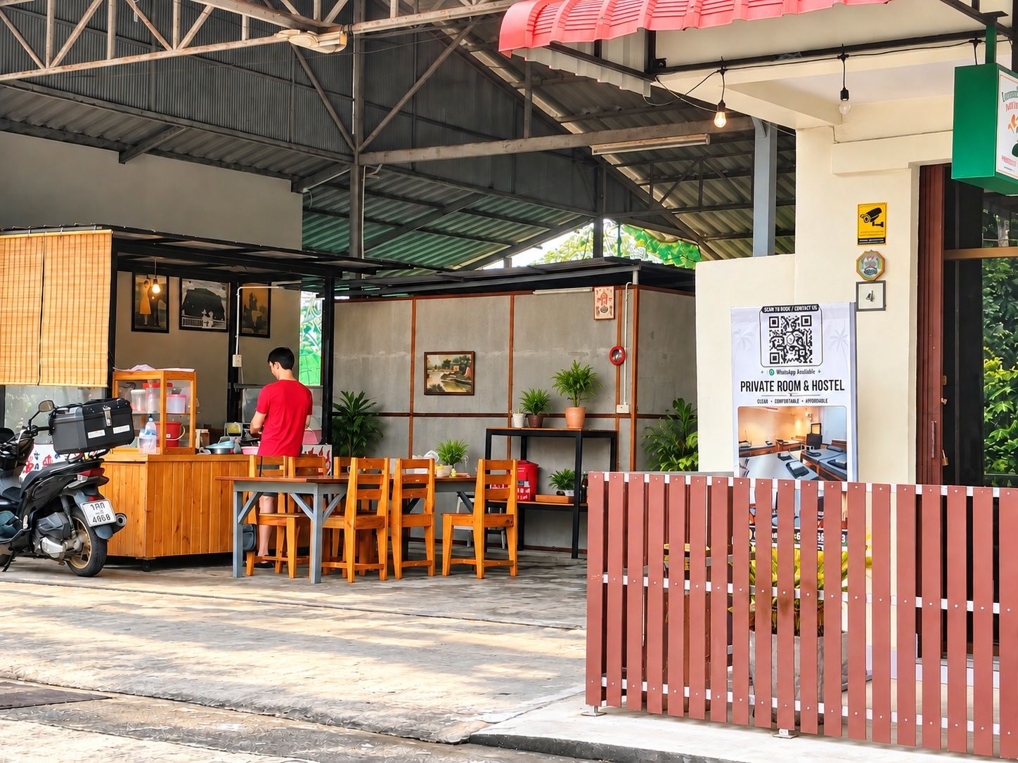 A private room and hostel with a wooden table and chairs, a motorcycle, and a sign advertising the amenities.