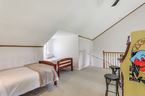 Un dormitorio con una cama individual, un banco de madera, dos taburetes y una escalera.