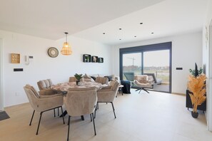 A modern living room with a dining area, large windows, and a view of the cityscape. - La Casa Alegría, a luxury 3-bedroom apartment (San Javier)