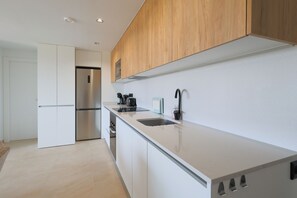 A modern kitchen with white cabinetry, a stainless steel refrigerator, a built-in oven, and a black faucet. - La Casa Alegría, a luxury 3-bedroom apartment (San Javier)
