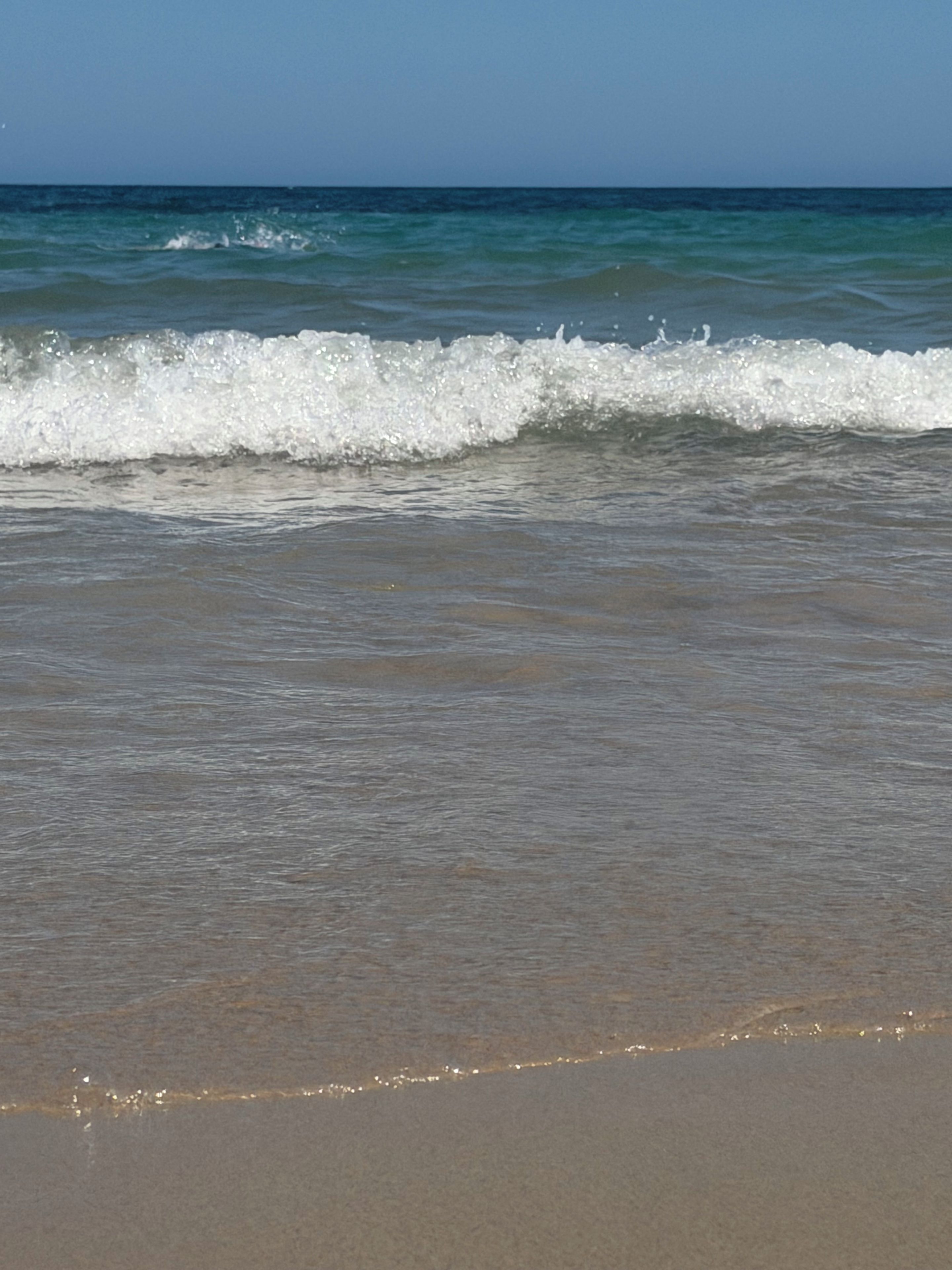 A beach with waves approaching the shore.