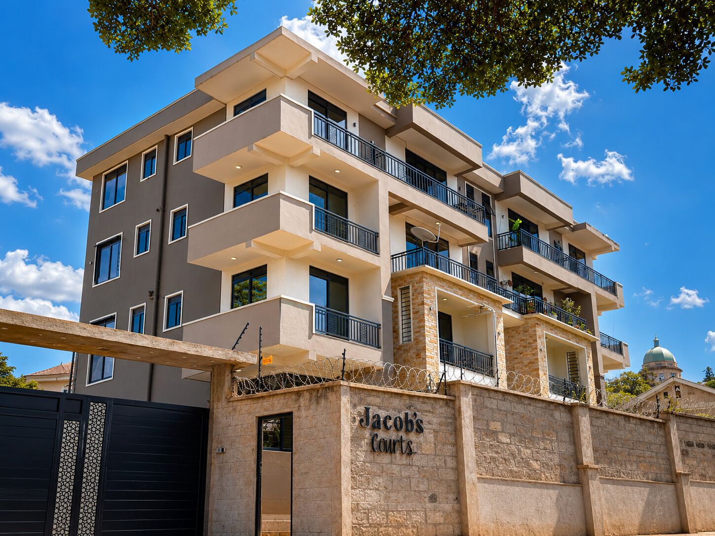 Un immeuble résidentiel à plusieurs étages, doté d’une façade en pierre, de nombreux balcons et surplombant un ciel dégagé.