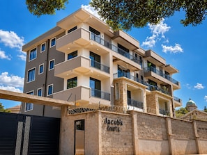 Un edificio residencial de varios pisos con fachada de piedra, múltiples balcones y cielo despejado.