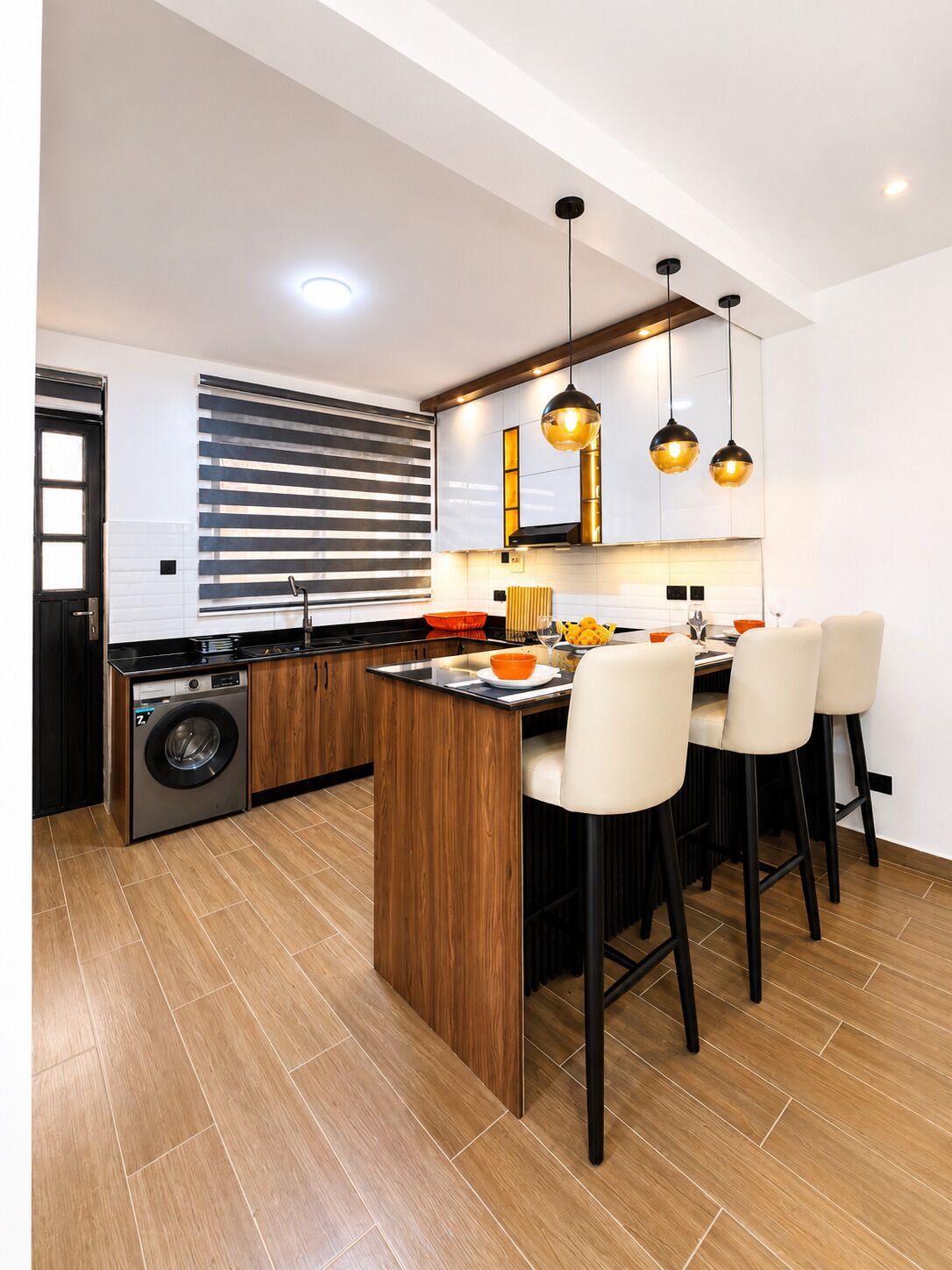 Una cocina moderna con una isla central, armarios de madera e iluminación colgante.