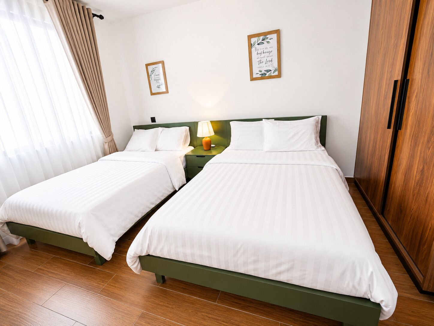 A hotel room with two single beds, a nightstand with a lamp, and a wardrobe.