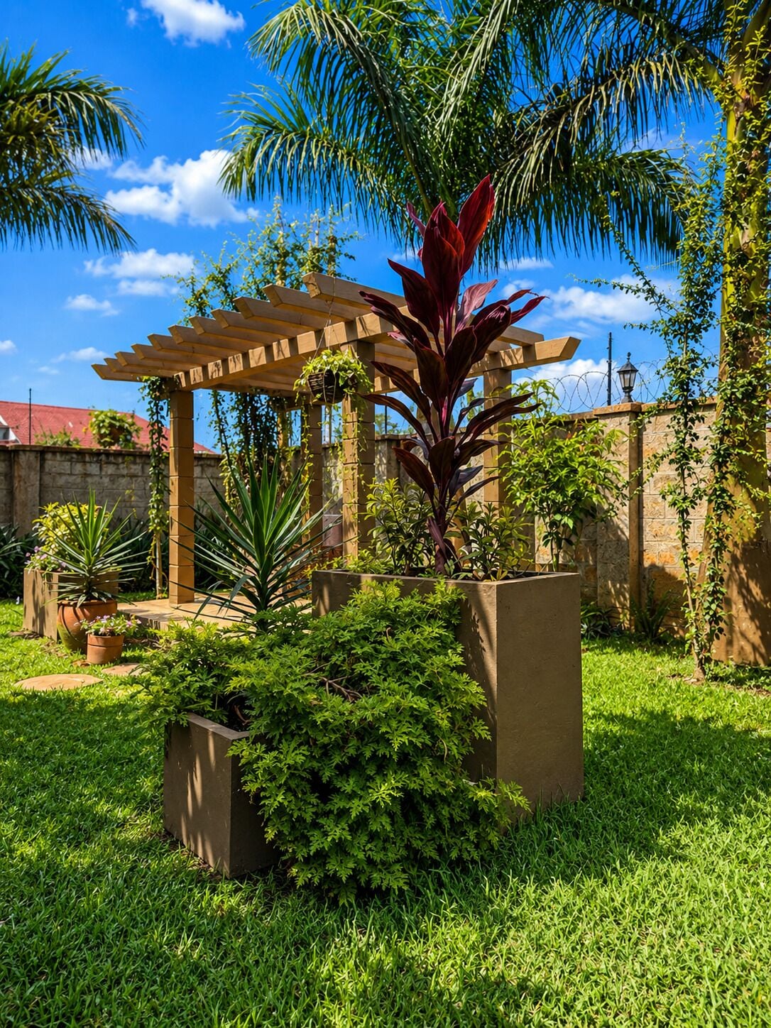Un jardín con un pérgola, distintas plantas y un cielo azul despejado.