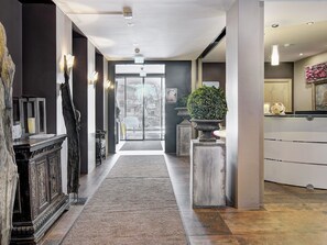 Un moderno vestíbulo de hotel con un pasillo central, una recepción y un amplio ventanal.