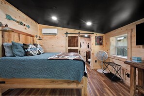 Ein Zimmer mit Holzeinrichtung, einem Bett, einem Ventilator und einem Fenster.