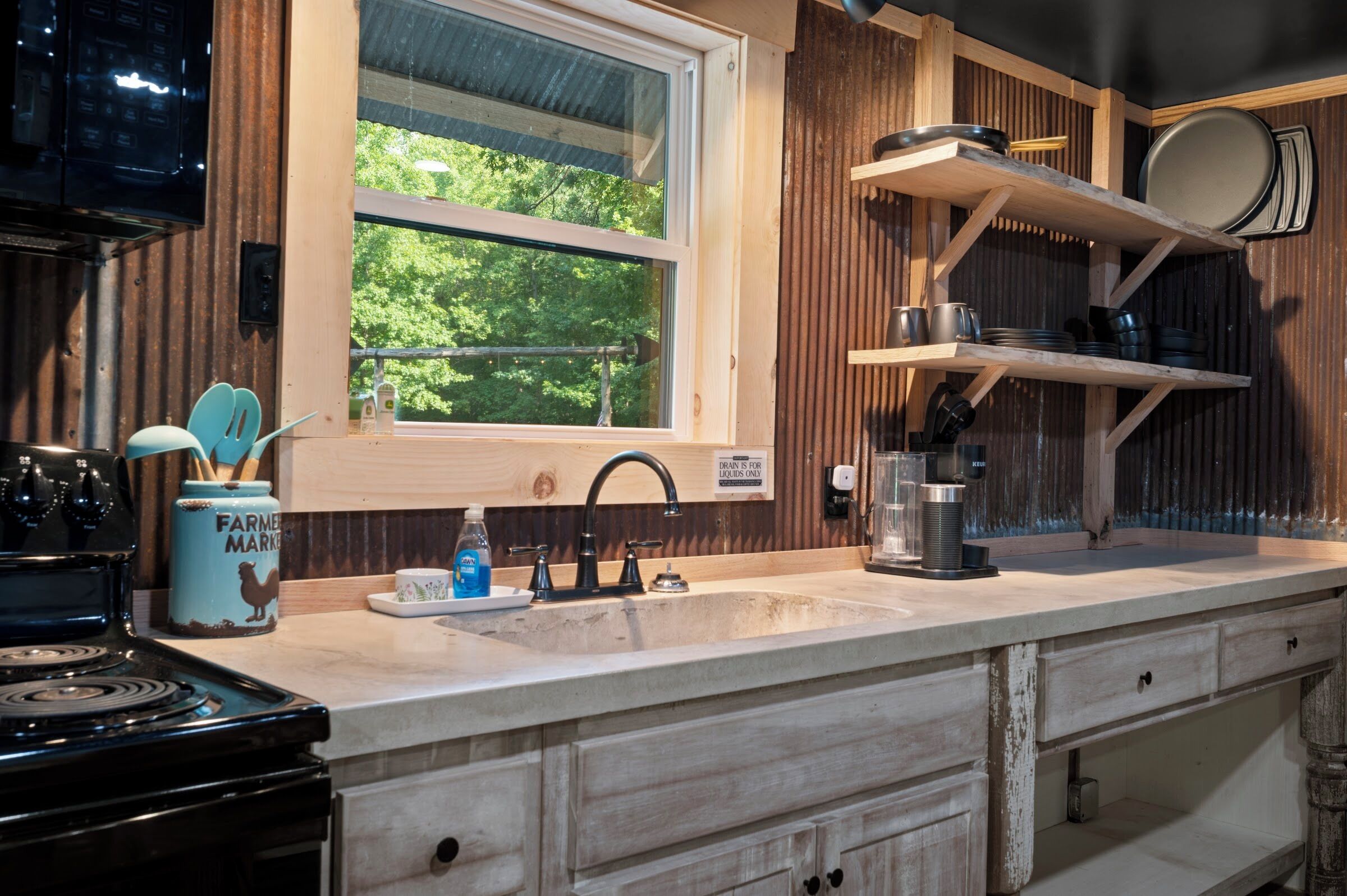A kitchen with a window, wooden cabinets, a stove, and a sink.