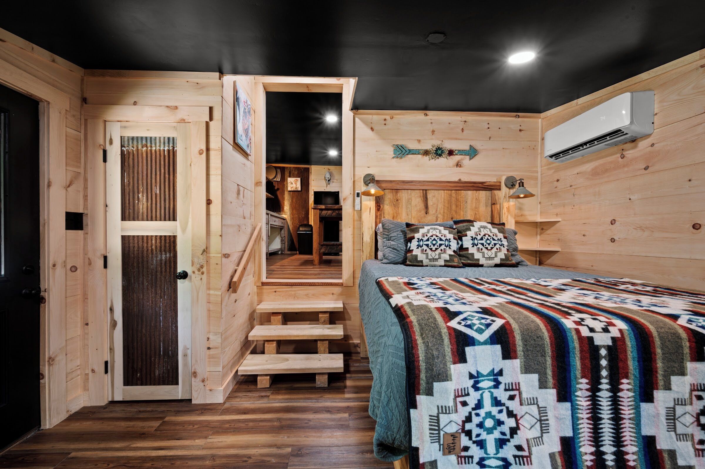 A wooden room with a bed, a staircase, and an air conditioning unit.