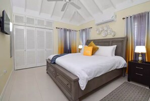 Un dormitorio con cama, mesitas de noche, ventilador de techo, armario y cortinas.