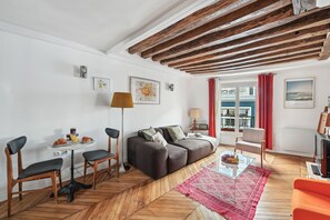 Ein Wohnzimmer mit Fischgrätparkett, einer Couch, einem Couchtisch und einem roten Teppich.