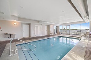 Piscina com vista clara do céu, porta com porta-toalhas e um banco à beira da piscina.